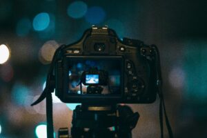 Close-up of a DSLR camera capturing a bokeh background in a dimly lit setting, illustrating night photography.