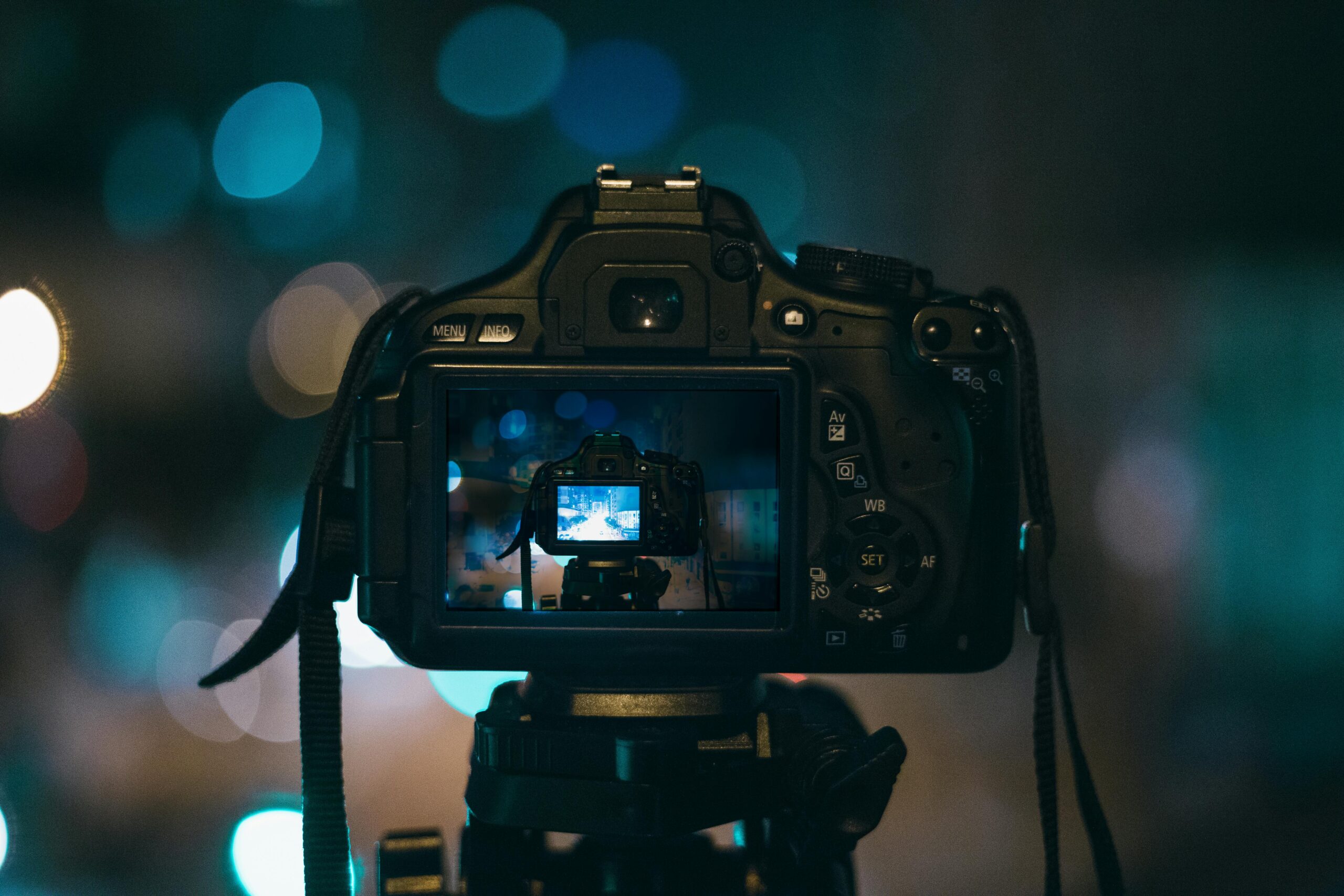 Close-up of a DSLR camera capturing a bokeh background in a dimly lit setting, illustrating night photography.